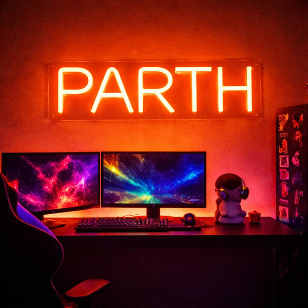 Neon sign with 'PARTH' on a desk setup with two monitors and a decorative figure.
