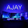 Neon sign with 'AJAY' in a dark room with computer monitors and equipment.