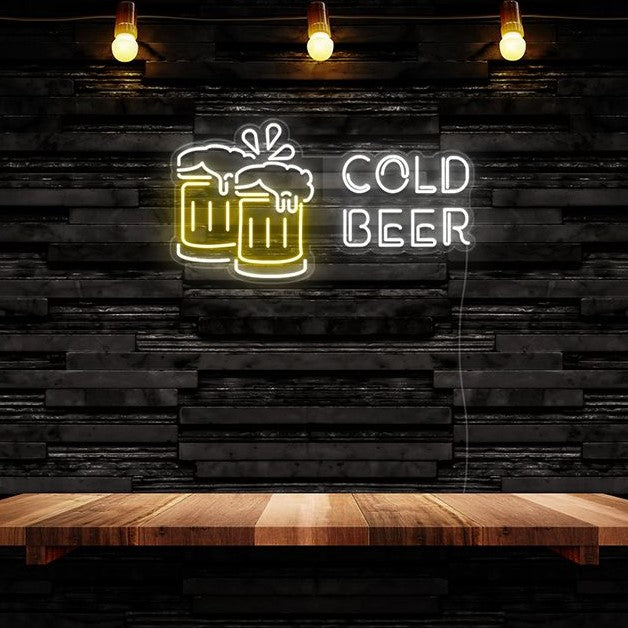 Neon sign with 'Cold Beer' text and beer glass icons on a wooden table against a dark wooden wall.

