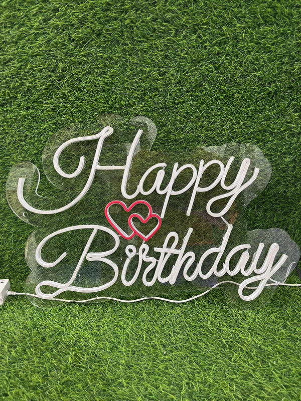 Neon sign with 'Happy Birthday' on a grass background
